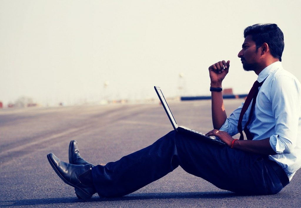 a man sitting on the ground with a laptop