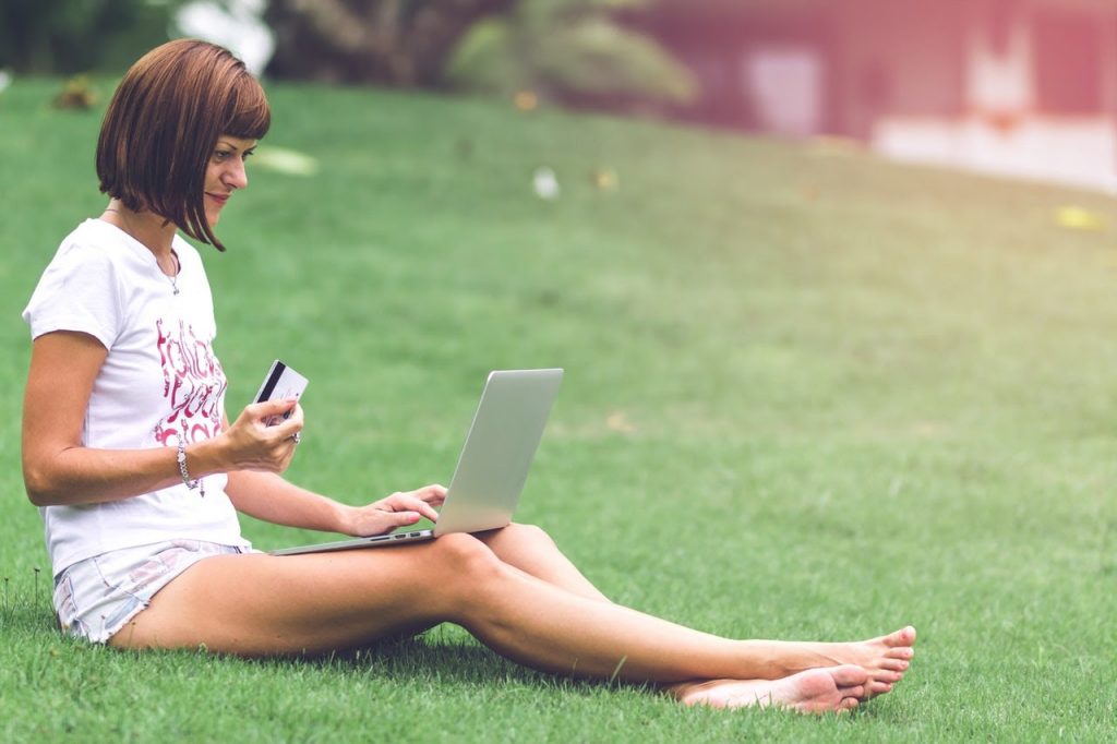 a woman sitting on the grass using a laptop