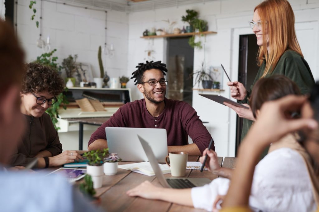 a group of people sitting around a table with laptops
