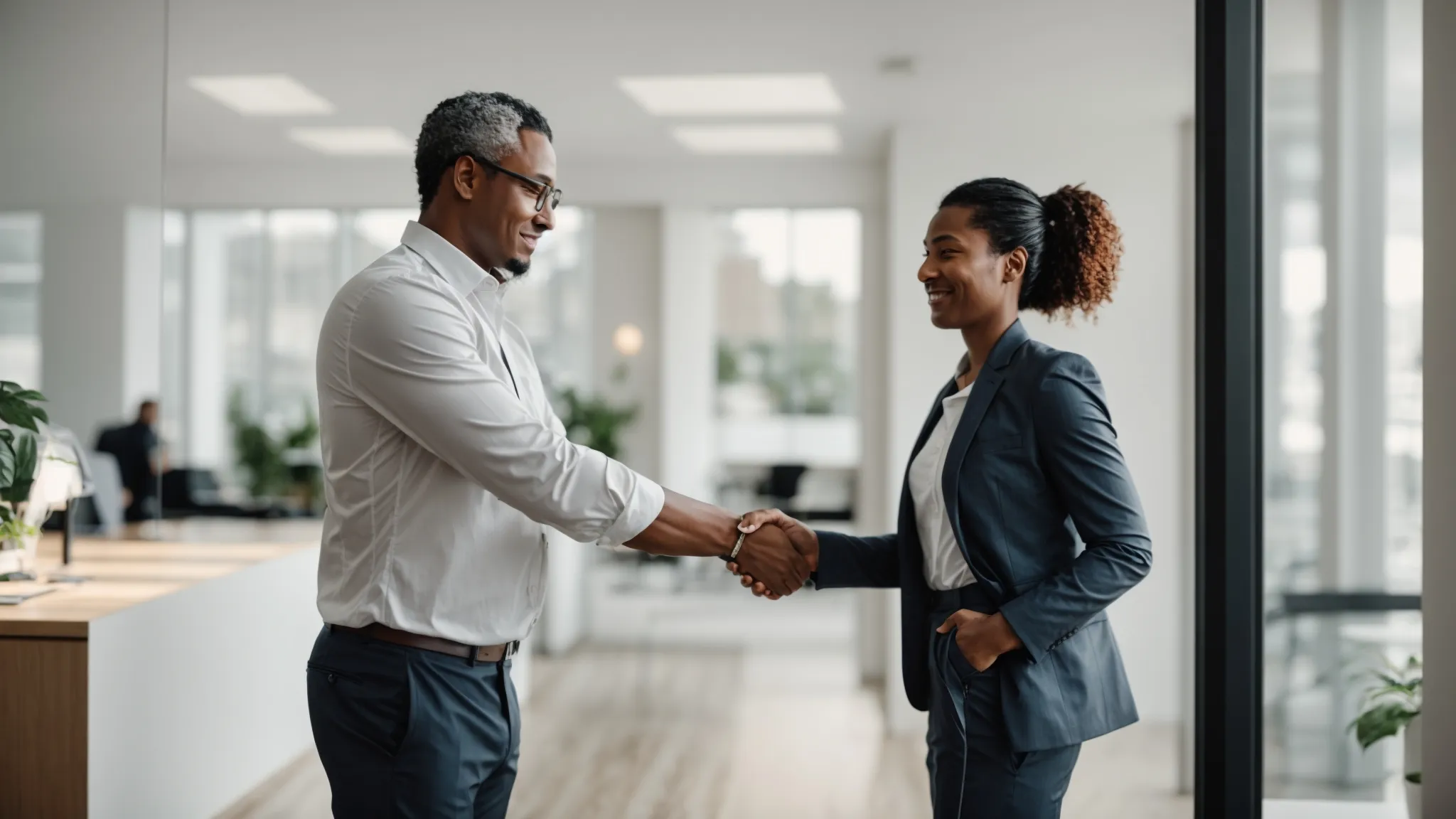 a business owner shakes hands with an insurance agent in a bright, modern office.